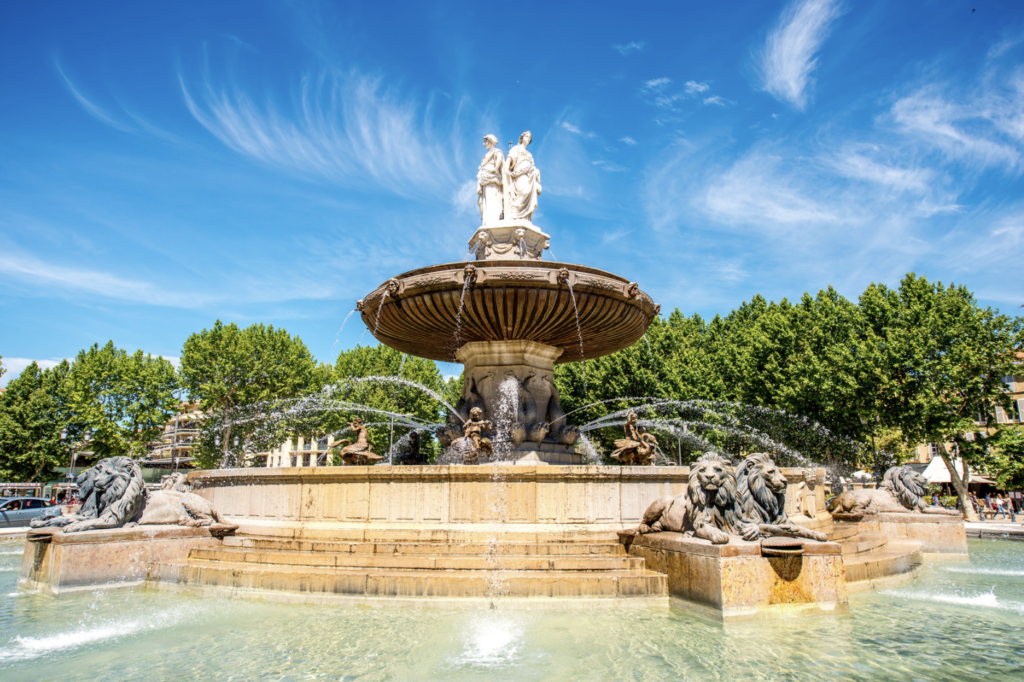 "The Rotonde in Aix-en-Provence, a stunning fountain surrounded by lush greenery and historic architecture, representing the lively heart of this charming Provençal city."